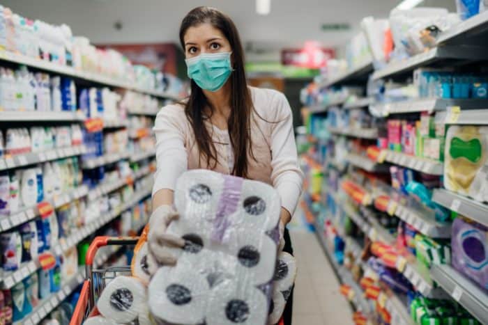 Shopper grabbig excess toilet paper regarding price gouging amid COVID-19