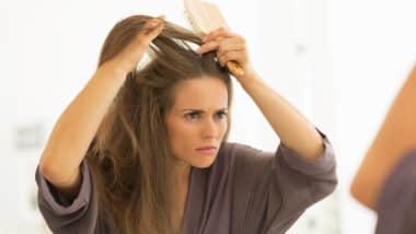 Concerned young woman combing hair in bathroom
