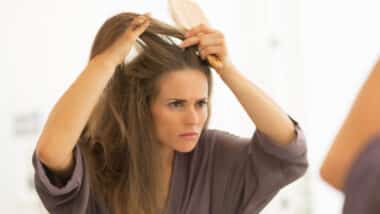 Concerned young woman combing hair in bathroom