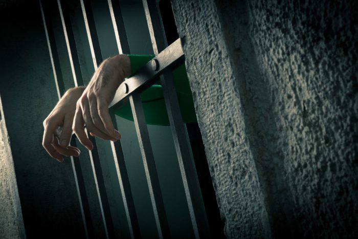 a woman behind bars claims her head covering was removed for mug shots