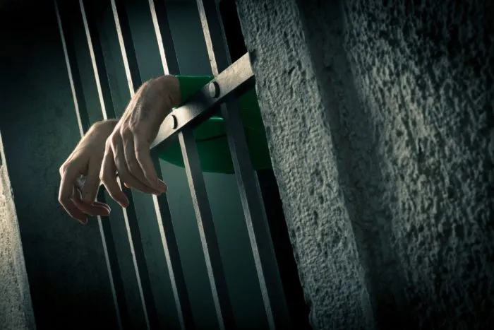 a woman behind bars claims her head covering was removed for mug shots