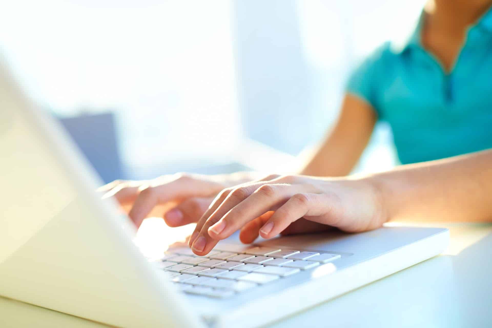 A woman in an aqua shirt uses a white laptop - privacy rights