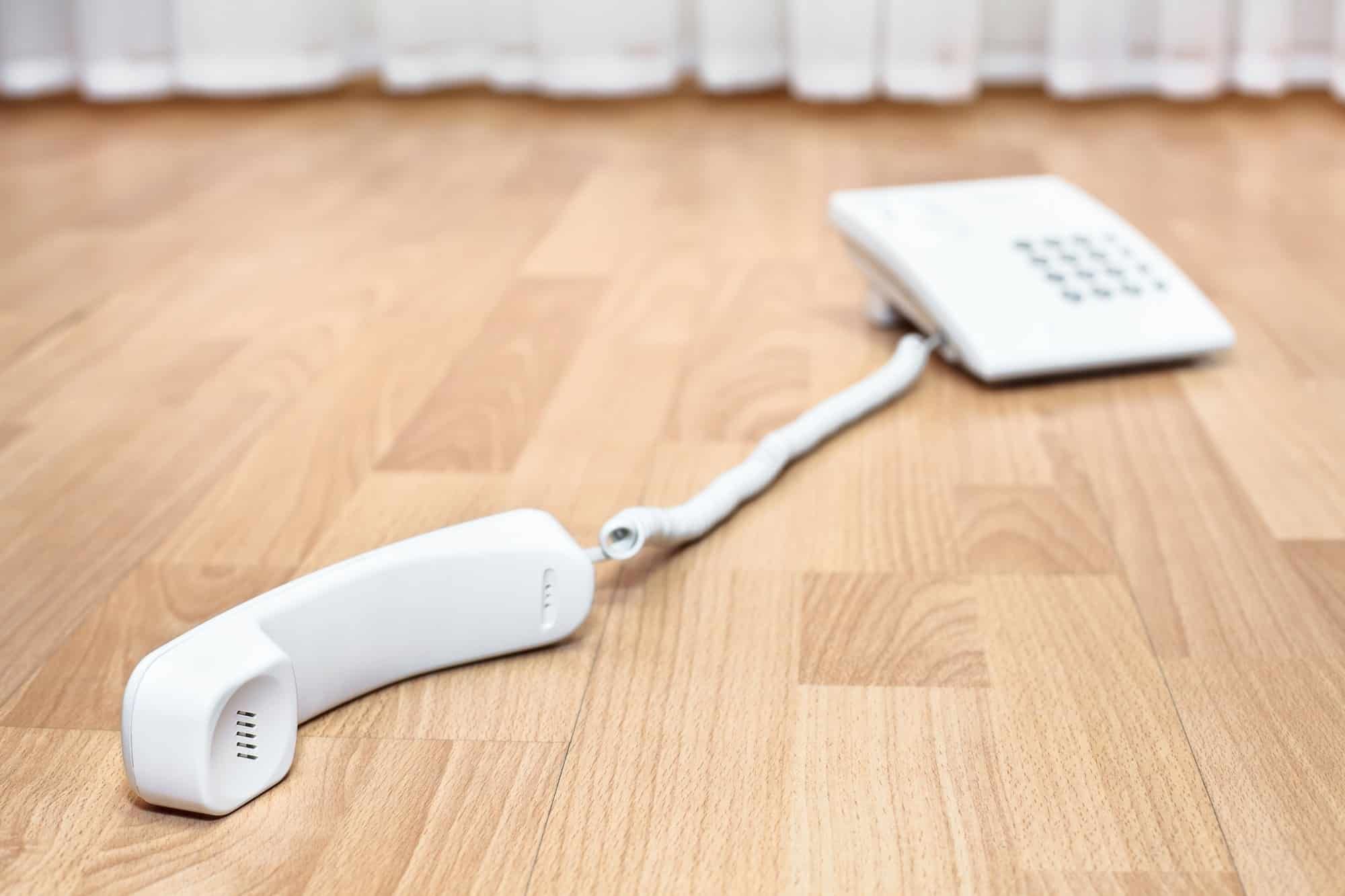 White landline phone lying on a wood floor with the receiver off the hook - palo alto utility