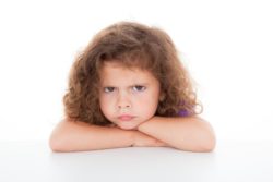 Unhappy little girl sits with arms crossed