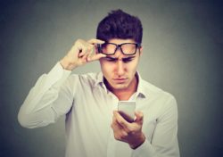 Man is looking at his phone after receiving an unwanted text from a marijuana dispensary in California.