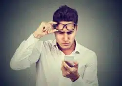 Man is looking at his phone after receiving an unwanted text from a marijuana dispensary in California.