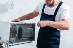 Man repairing broken Sharp microwave.
