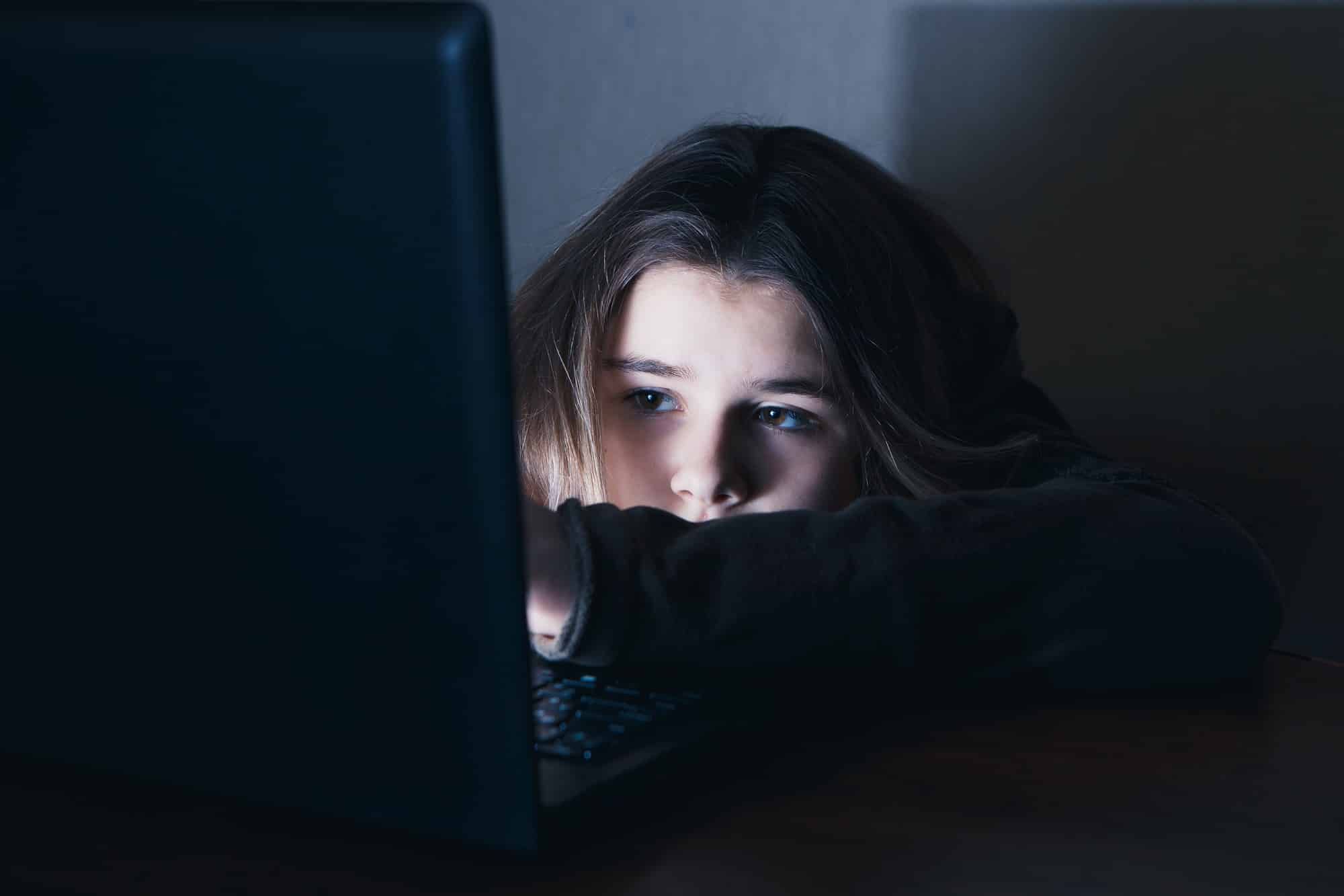 A homeless teenage girl tries to use the internet on her laptop.