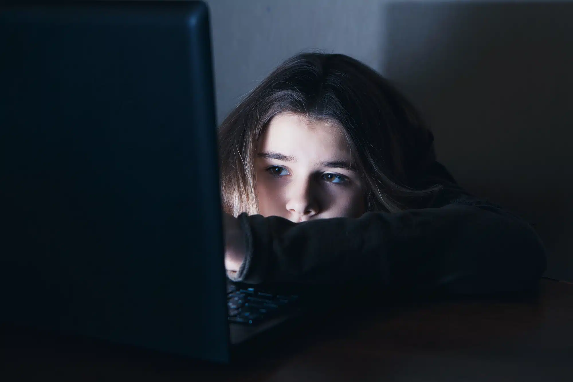 A homeless teenage girl tries to use the internet on her laptop.