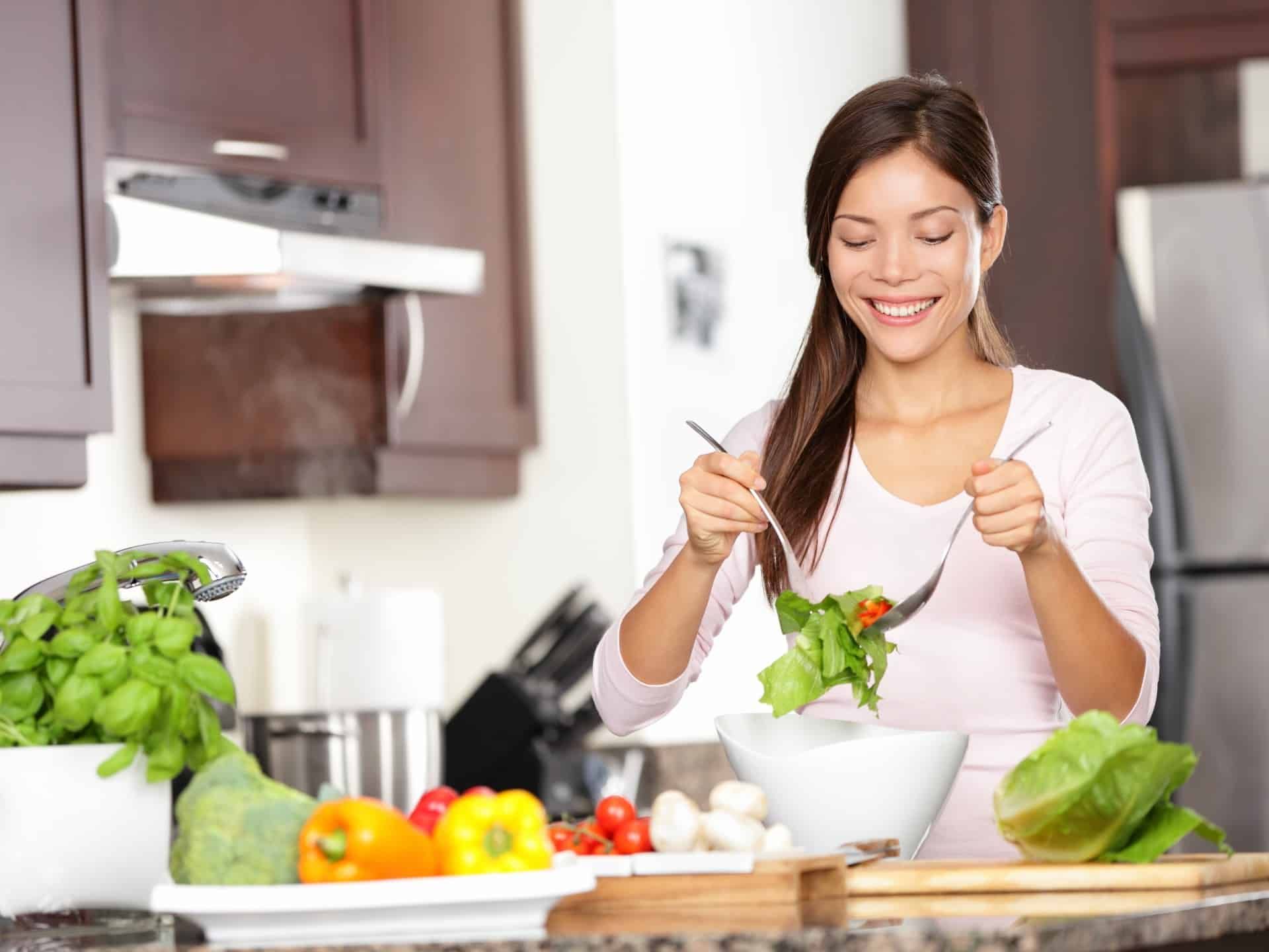 A smiling woman makes a salad
