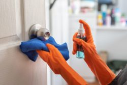 Woman wearing orange gloves while using Soho Fresh rubbing alcohol.