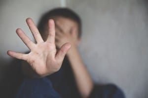 Boy holds up a palm to the camera while hiding his face with his other hand - Boys and Girls Club of America