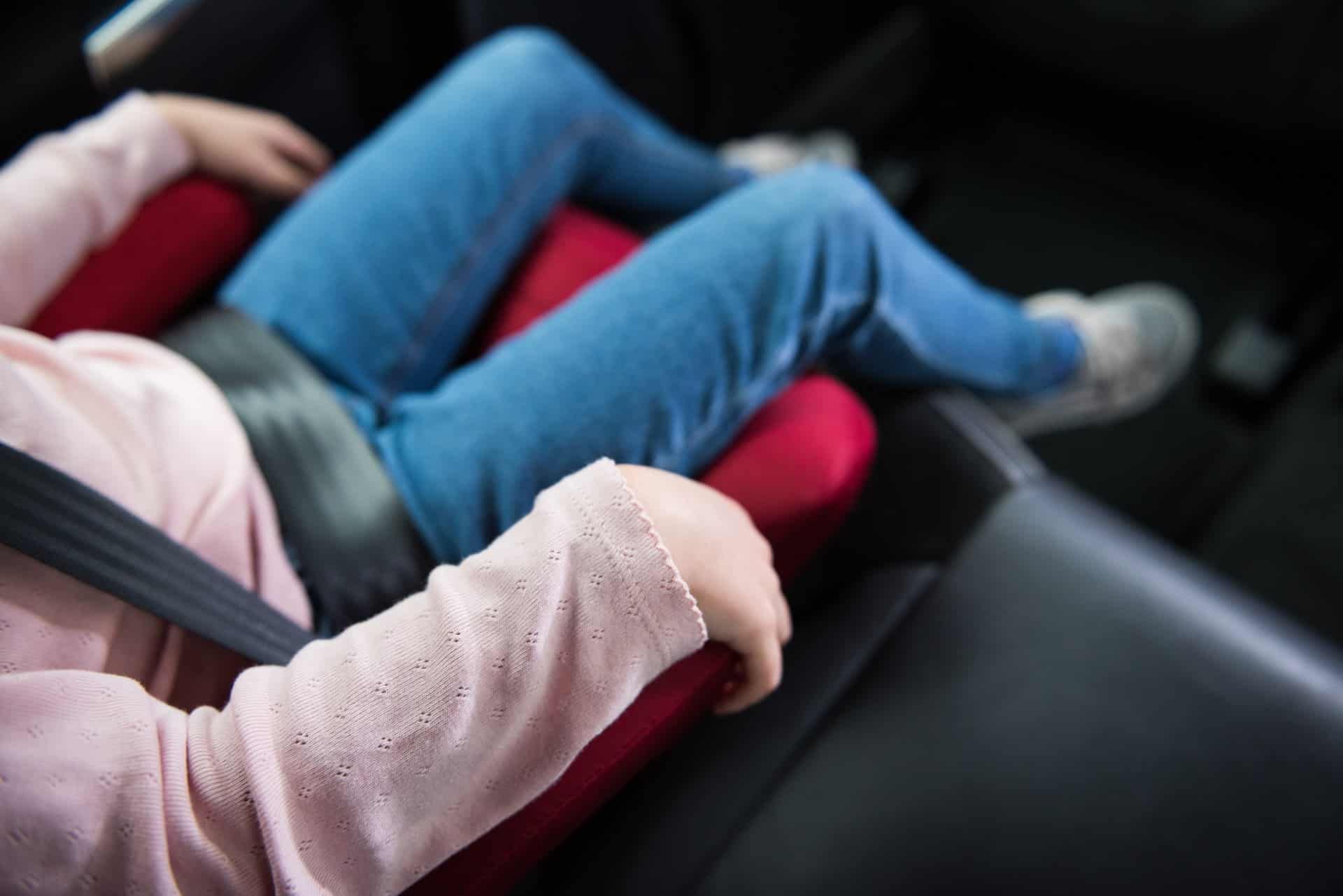 A child sits buckled into a car booster seat