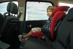 A boy sits in a car booster seat