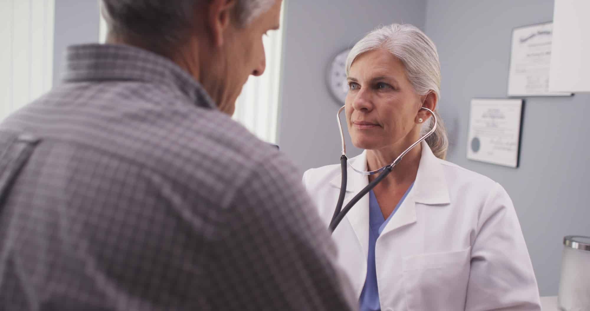 female doctor checking male patient heart