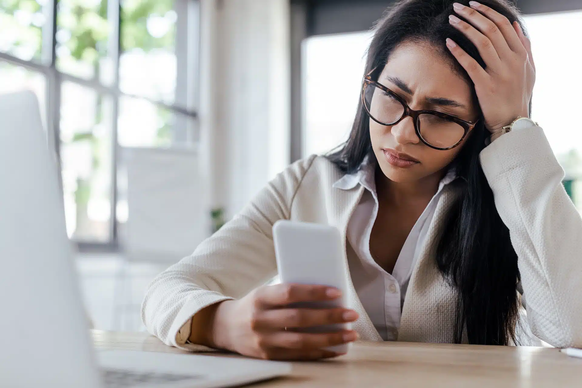 Frustrated woman sits with head in one hand while holding smartphone with the other - data throttling