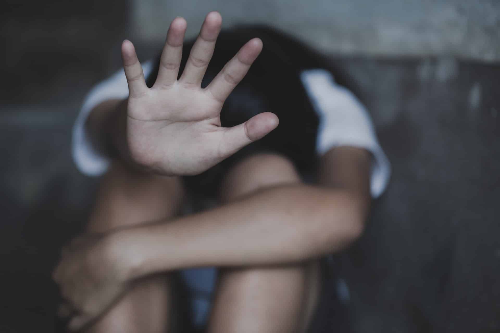 Young person hiding their face holds their palm up toward the camera - ymca