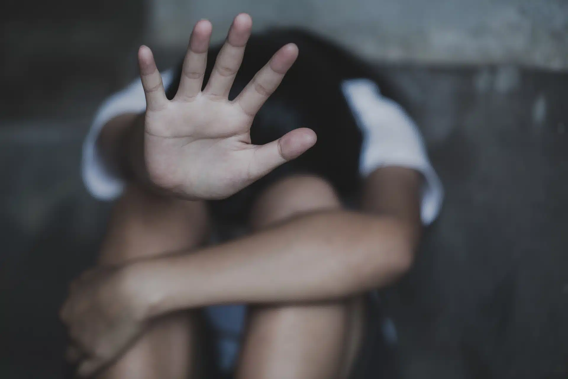 Young person hiding their face holds their palm up toward the camera - ymca