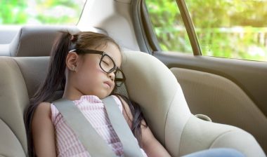 Young girl in glasses sleeps in a car seat - booster seat