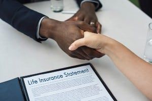 Two people shake hands over a life insurance statement - paclife