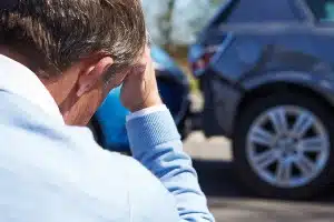 Man holds his head in his hand as he looks at auto accident - diminished loss