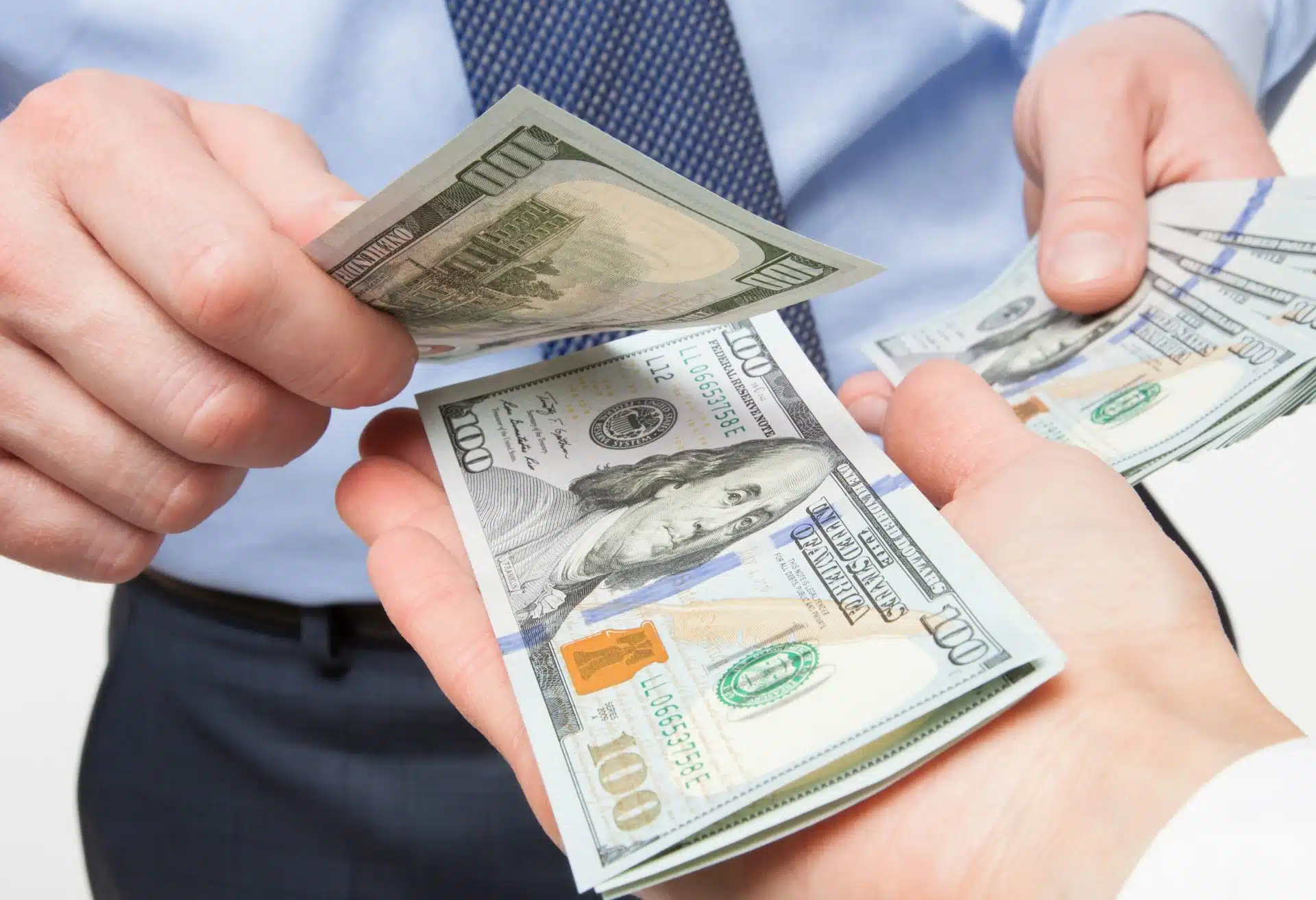 A man counts out $100 bills into someone's hand - class action settlements - refunds