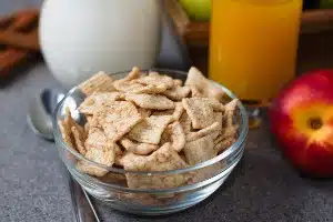 Cereal in a bowl alongside other breakfast items - cinnamon toast crunch
