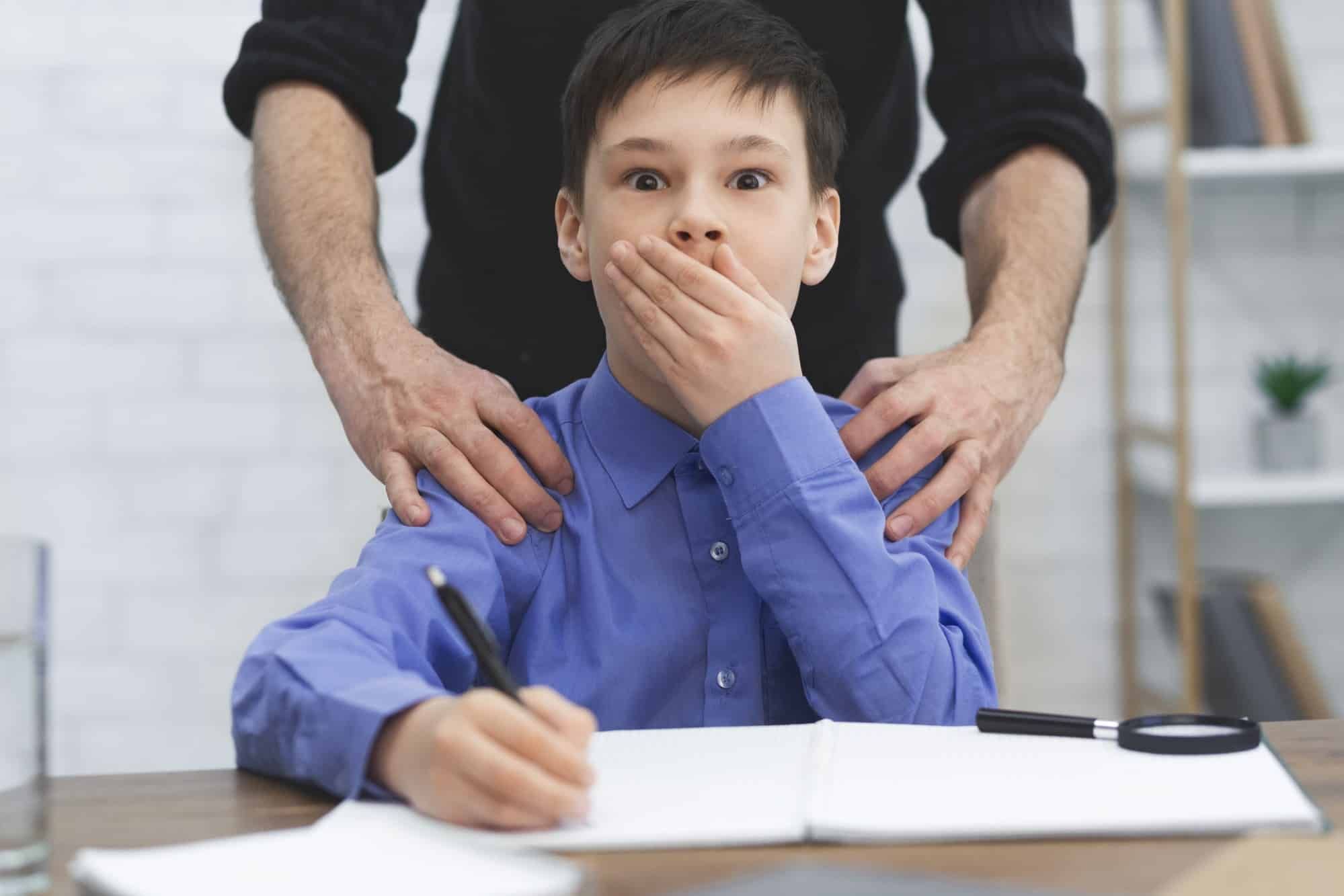young boy covering mouth, hidden abuse