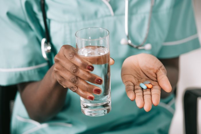 close up of hands with pills and water