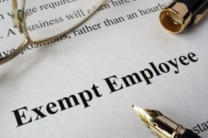 A paper reads "Exempt Employee," and a pen and pair of glasses lie on top - gallagher