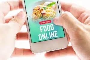 Hands on a smartphone showing a food delivery app screen - delivery fees