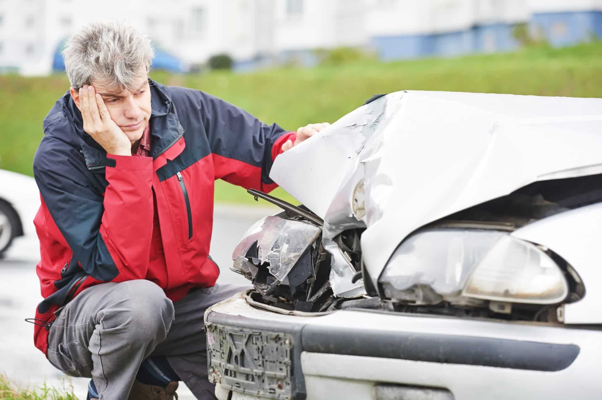 A sad man looks at the damage to his vehicle after a collision - car totaled in texas