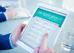 Closeup of a man holding a tablet showing an online job application - Quantum Global Technologies LLC