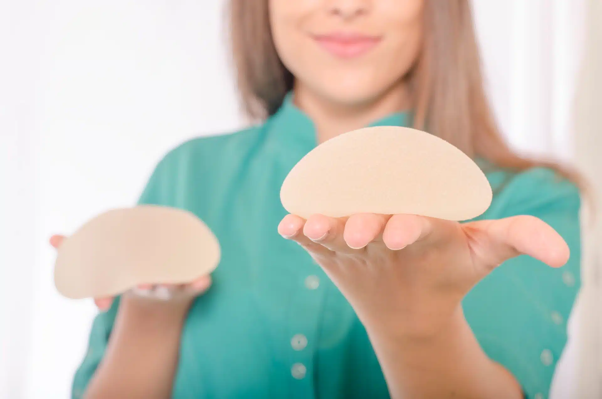 A woman holds two breast implants - allergan