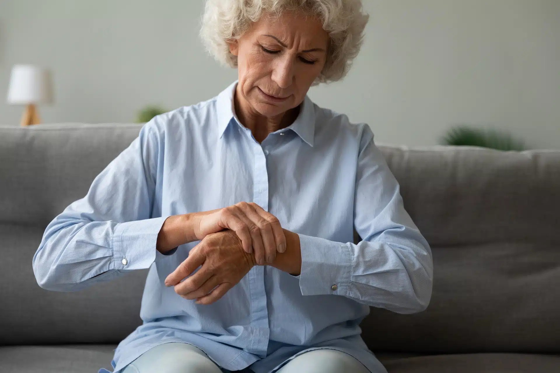 An upset older woman grabs her left wrist with her right hand - walmart glucosamine joint supplements