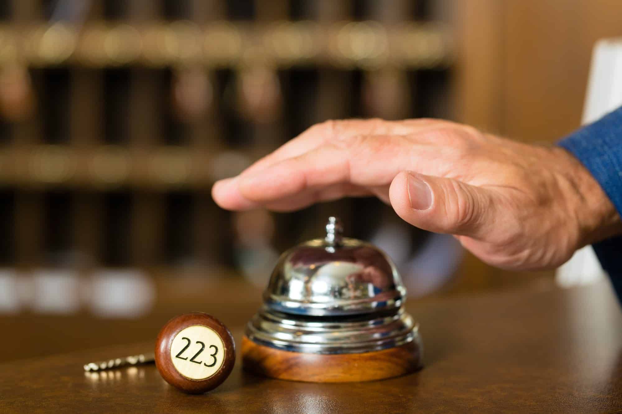 man's hand ringing bell at hotel reception desk