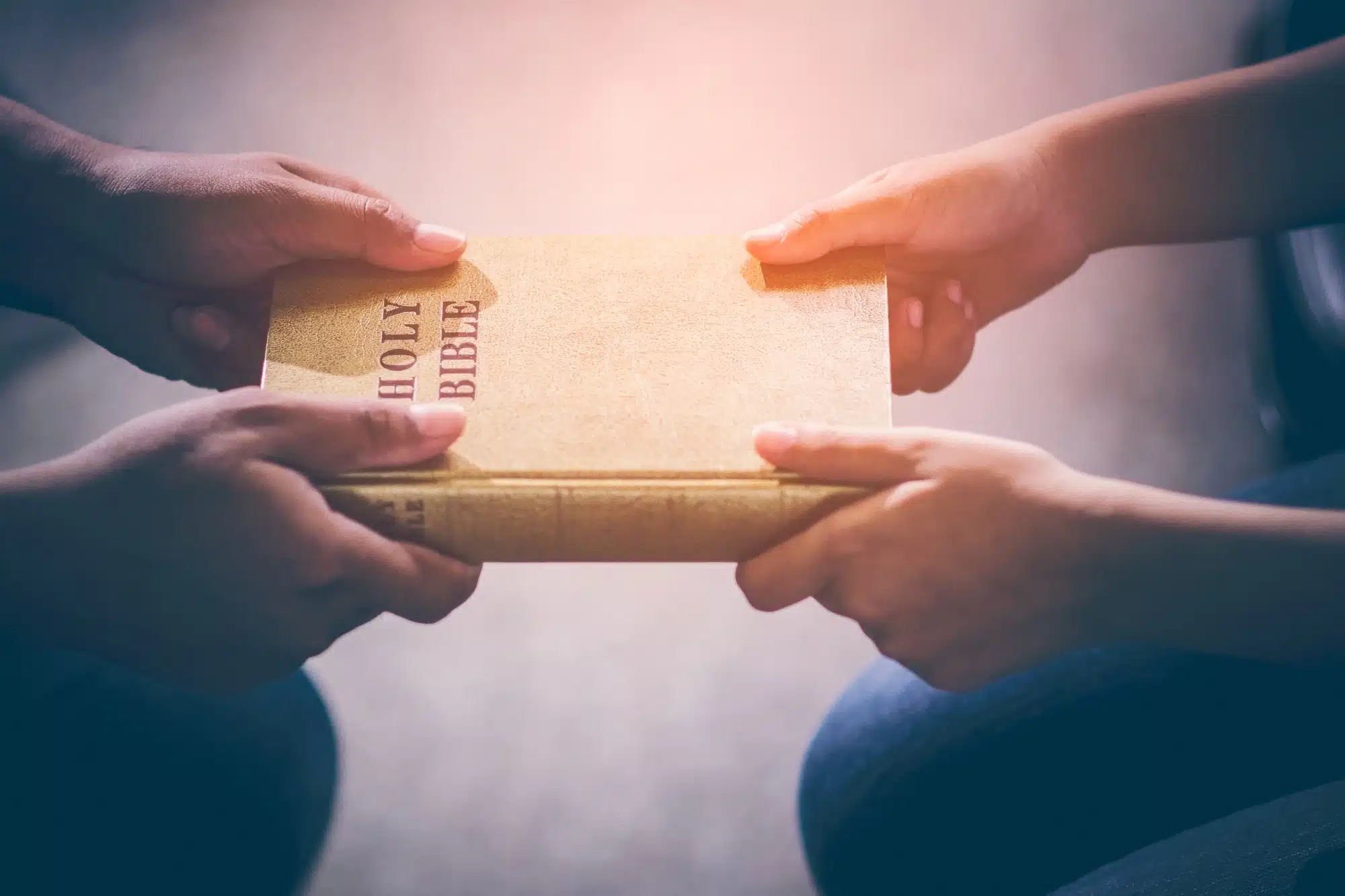 two people holding holy bible, hands close up