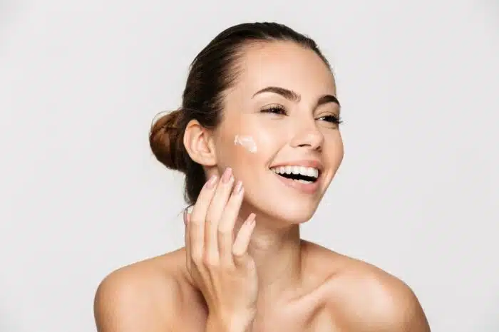 A smiling woman applies face cream - tula life inc.