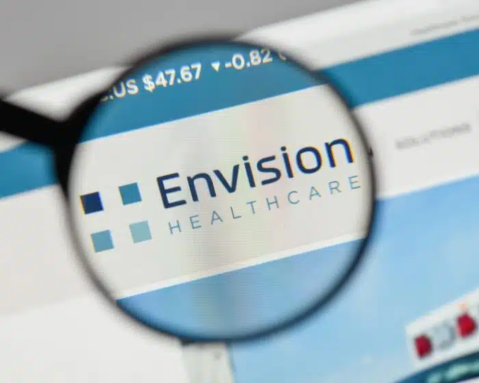Envision Healthcare logo on a screen, under a magnifying glass - envision emergency - Envision lawsuit - Envision class action