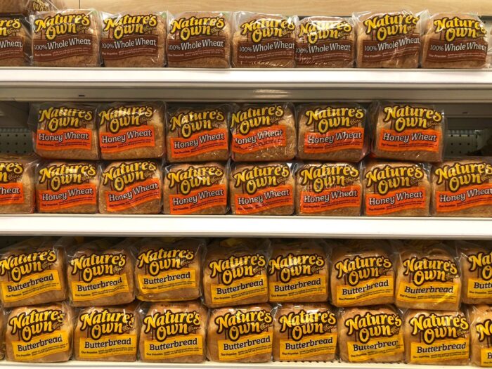 Grocery store shelf with bags of Natures Own brand bread.