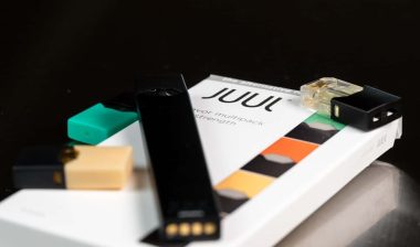 Juul e-cigarette or nicotine vapor dispenser box and JUULpod on dark background