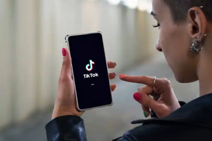 Women holding Phone with TikTok logo on the screen.