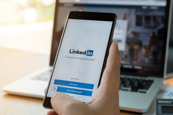 A phone screen shows the LinkedIn app, representing the LinkedIn monopoly class action lawsuit.