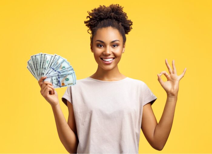 Smiling girl shows money cash and excellent sign