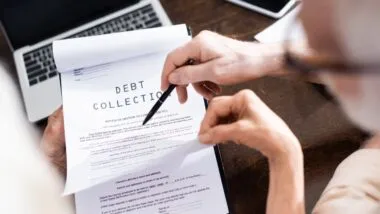 Selective focus of senior man holding pen near wife with debt collection lettering on papers