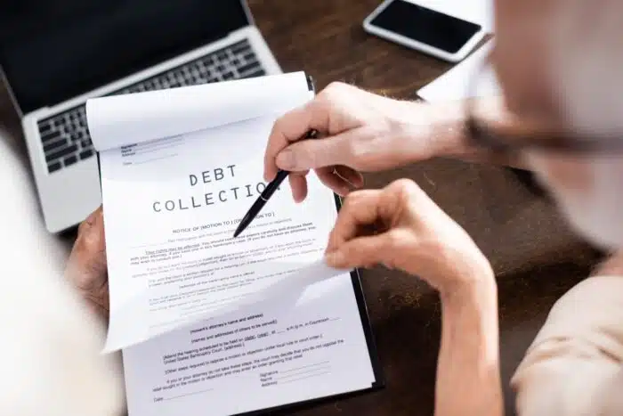 Selective focus of senior man holding pen near wife with debt collection lettering on papers