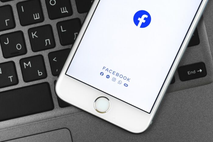 Facebook app on Apple iPhone screen, background of keyboard, photo