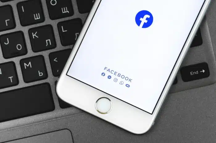 Facebook app on Apple iPhone screen, background of keyboard, photo