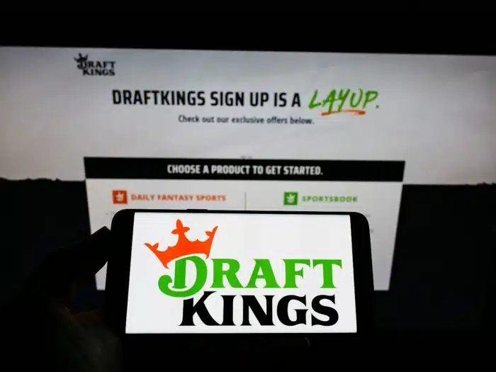 Person holding smartphone with logo of US sports betting company DraftKings Inc. on screen 