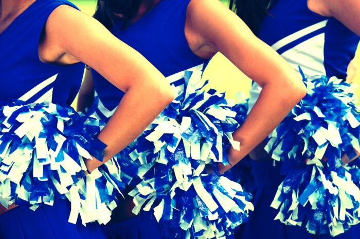 Cheerleaders in Uniform Holding Pom-Poms